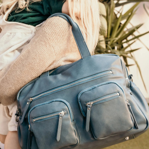 Mum carrying the carry all nappy bag in stone blue