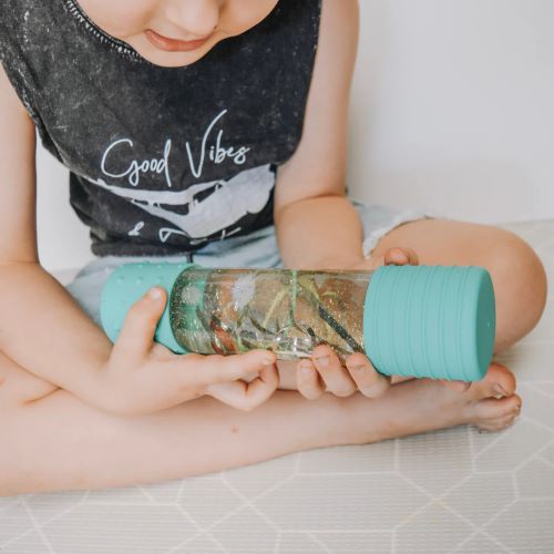 Little boy playing with a diy calm down bottle in mint