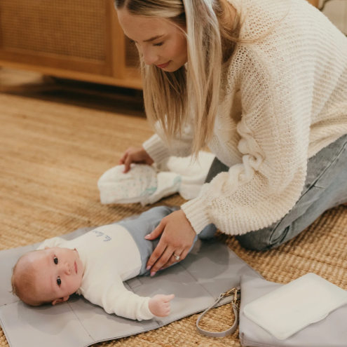Mum changing a baby on a changemat out of the nappy pouch