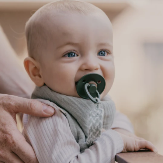 Baby using a pacifier clip and dummie