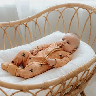 Baby in bassinet wearing bamboo zipsuit in bumble bee print