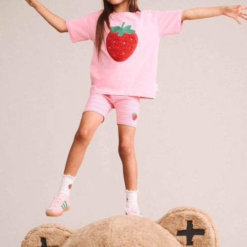 girl standing on a bear wearing the strawberry slouchy tee
