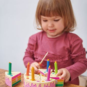 little girl playing with the rainbow birthday cake
