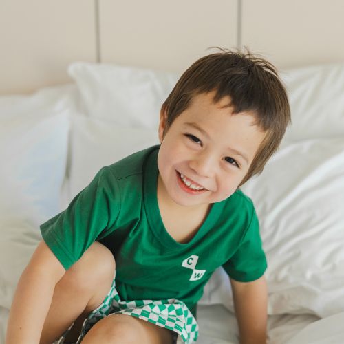 Little boy on bed wearing short sleeve sleep set sea green check