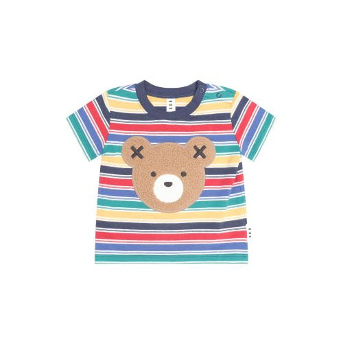 A toddler's short-sleeve striped t-shirt featuring a brown teddy bear face graphic on the front. The shirt has horizontal stripes in multiple colors including blue, green, yellow, orange, and red, with a navy blue collar.