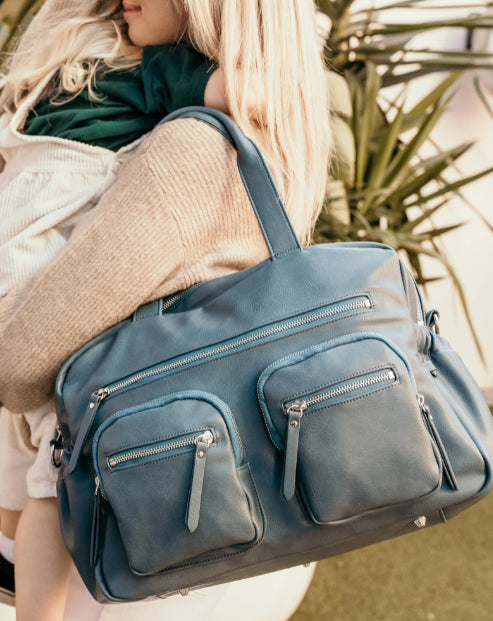 Mum carrying the carry all nappy bag in stone blue