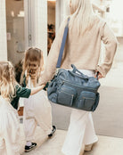 mum carrying the carry all nappy bag in stone blue