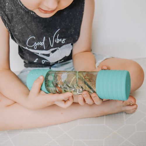 Little boy playing with a diy calm down bottle in mint 