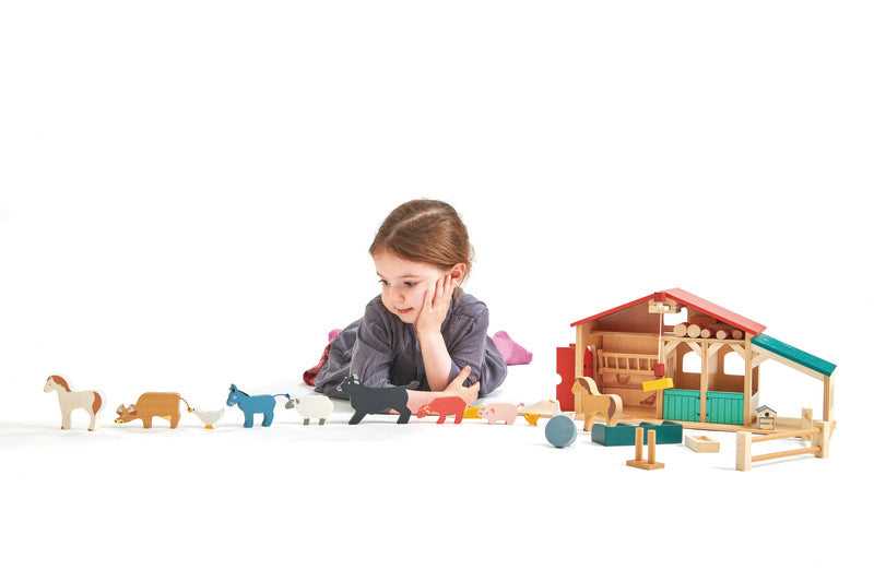 Little girl playing with the wooden farm