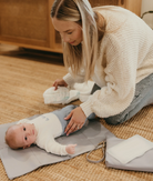 Mum changing a baby on a changemat out of the nappy pouch