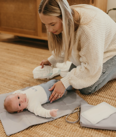 Mum changing a baby on a changemat out of the nappy pouch