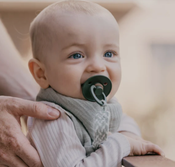 Baby using a pacifier clip and dummie