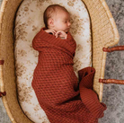 Baby wrapped in rust baby blanket