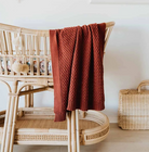 Rust diamond baby blanket hanging over bassinet