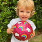 Little kid with a glitter soccor ball in a rainbow and cloud design