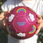 Child holding a rainbow and cloud design glitter soccor ball