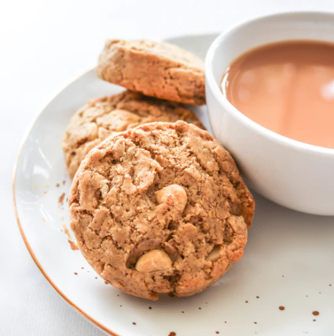 Made to milk white choc & macadamia lactation cookies on a plate with a cup of tea.