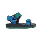 A kids' sandal from the brand Calvin Klein, shown in profile against a solid white background. The sandal features a black footbed and heel counter, bright blue adjustable straps with green accents, and a dark gray sole with a green edge.