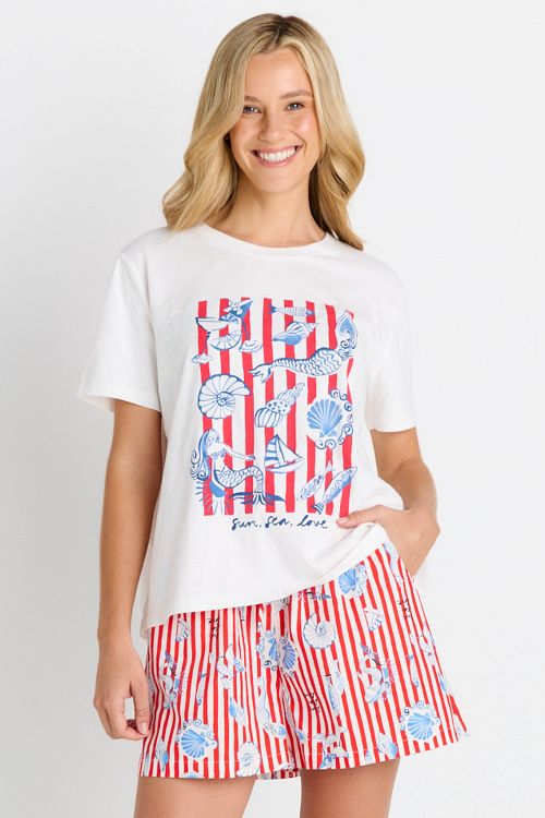 A woman modeling a white graphic t-shirt and matching red, white, and blue striped swim shorts against a plain white background.
