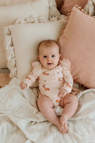 BAby wearing frilly bodysuit in classic fawn print