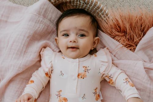 Baby wearing frilly bodysuit in classic fawn print