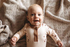 Baby wearing henley bodysuit in brown hearts print