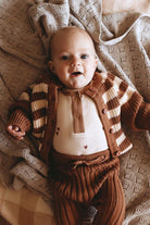 Baby wearing henley bodysuit in brown hearts print