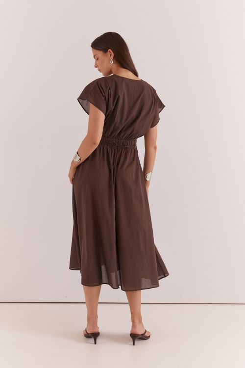 A woman wearing a dark brown midi dress with flutter sleeves and a gathered waist, shown from the back against a plain light background.