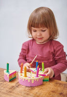 little girl playing with the rainbow birthday cake