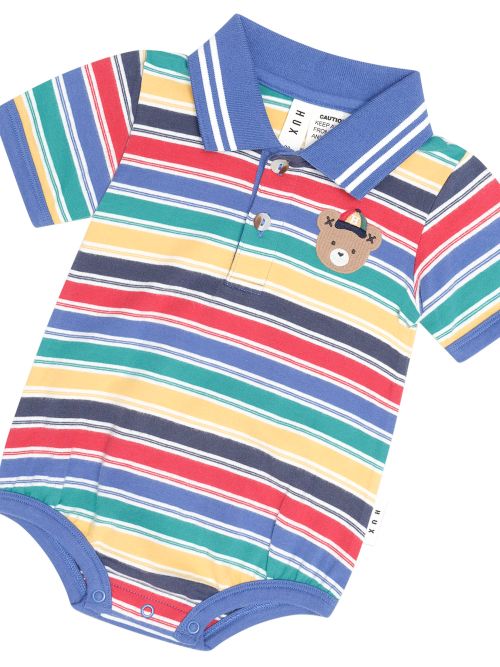 A baby short-sleeve polo romper with horizontal stripes in blue, red, green, yellow, and navy, featuring a small teddy bear patch on the chest and a blue collar.